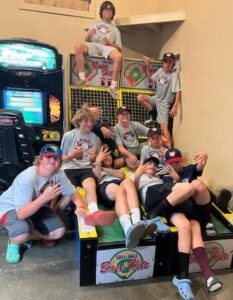 Kids in baseball caps piled onto an arcade game