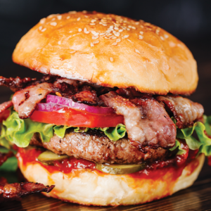 Bacon cheeseburger with lettuce and tomato on a sesame bun